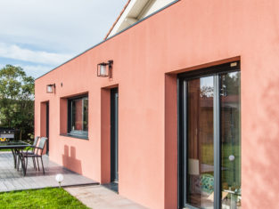 Extension d'une maison au couleur terracotta avec sa terrasse de couleur grise pour un rendu moderne
